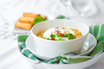 A bowl of spicy oriental noodles with poached egg