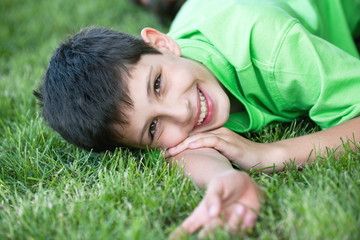 Smiling boy in green on the summer meadow