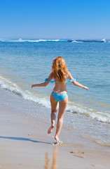 Fototapeta premium Young graceful woman goes on coast of ocean