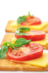 Fototapeta na wymiar Crackers with cheese, tomato and basil