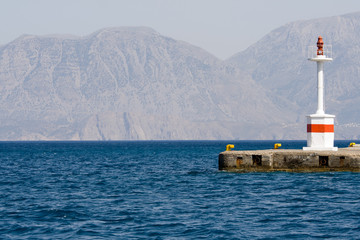 Lighthouse in rocky bay against the background of mountain