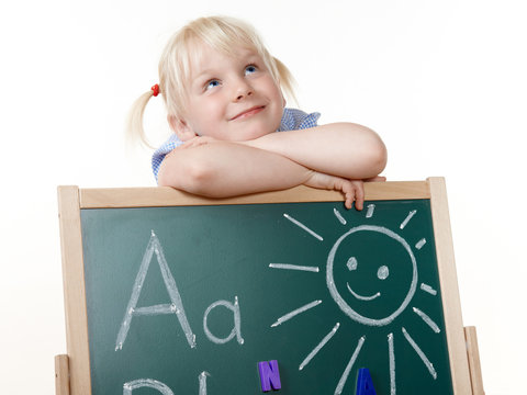 Sweet little girl writing the Alphabet on a blackboard