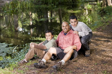 Portrait Hispanic father and sons outdoors by pond