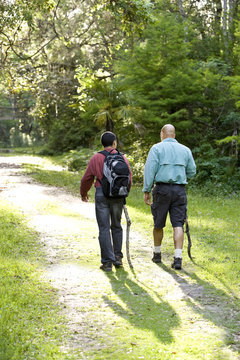 Rear view father and son hiking in woods on trail