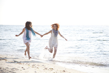 Two beautiful girls running on the beach.