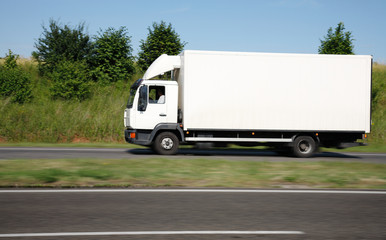 Fototapeta na wymiar White truck speeding on freeway , motion blurred.