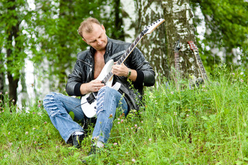 Naklejka na ściany i meble man playing guitar in a grass field