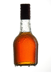 Bottle of cognac with water-drops on white background