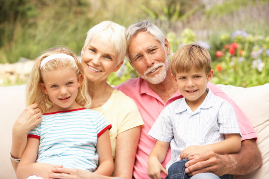 Grandparents And Grandchildren Relaxing In Garden