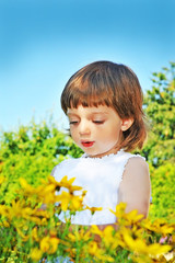 little girl (3 years old) looking on flowers in garden