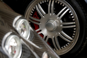 exotic car headlight with chrome wheel in the background