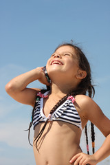 Small girl with mobile stay on summer beach