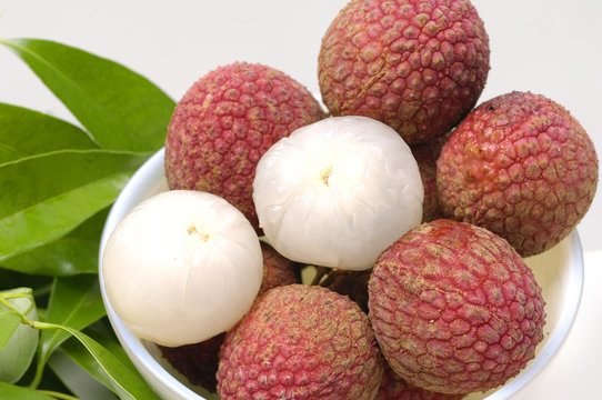 Bowl of Lychees and two peeled with leaf