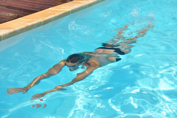 Jeune femme qui nage sous l'eau dans sa piscine