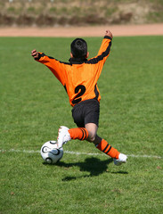 junger Fußballer schwebt mt Ball über den Rasen