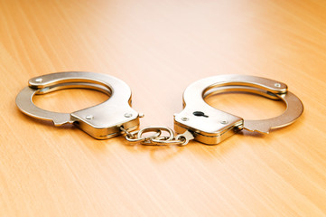 Metal handcuffs on the wooden background