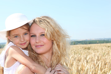 Mother and child in wheat field on sunny day