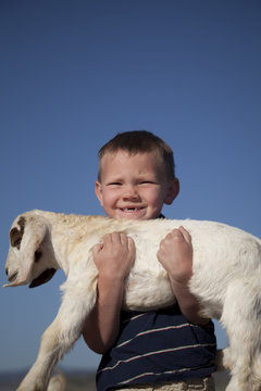 boy missing teeth with baby goat