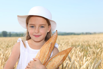 Closeup of little girl holding bread in wheat field