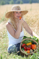 Beautiful woman with basket of vegetables in wheat field