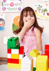 Child with wood block in play room.