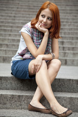 Portrait of beautiful red-haired girl on footstep.