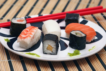 sushi su piatto tondo con bacchette rosse