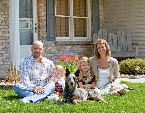 Family Sitting In Front Of Their Home