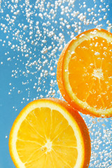 Fototapeta na wymiar Fresh orange dropped into water with bubbles