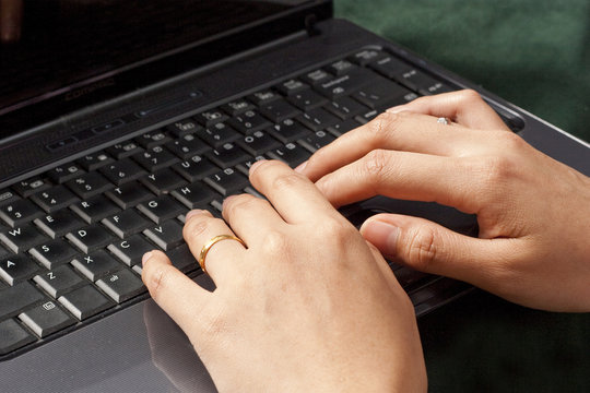 Female fingers typing on a black laptop