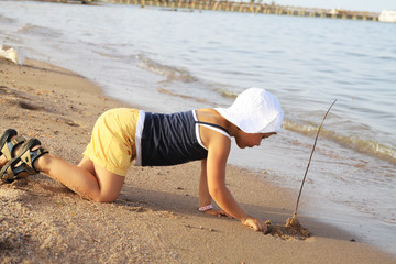 Young girl plays with stick on the beach