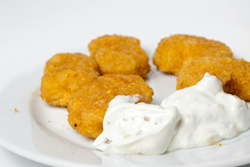 fried golden chicken nuggets on a plate with tartar sauce