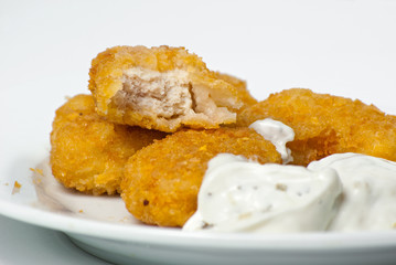 fried golden chicken nuggets on a plate with tartar sauce