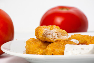 fried golden chicken nuggets on plate with tomatoes and tartar s