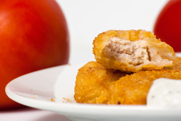 fried golden chicken nuggets on plate with tomatoes and tartar s