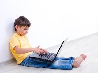 Little boy with laptop in empty room