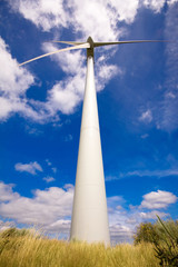 Fototapeta na wymiar Windmill in a field against a blue sky and clouds, alternative e