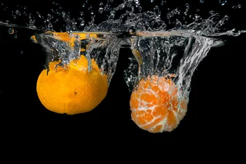  Verse mandarijnen vallen in water met bubbels op zwart © artjazz