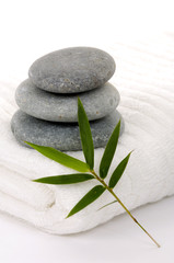 Fototapeta na wymiar bath towel and three stones balanced with lucky bamboo on white