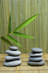 Fototapeta na wymiar bamboo leaf and a stack of stones on a bamboo mat