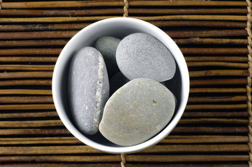 Zen stones in a bowl on bamboo mat