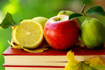 Apple and lemon on book.