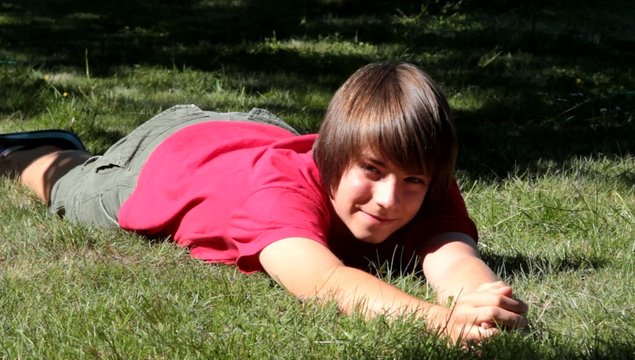 adolescent jouant avec son chat dans l'herbe