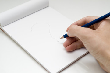 dibujando interrogante con un lapiz en un bloc de notas