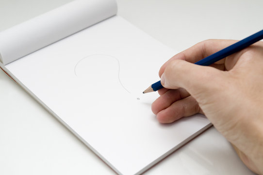 dibujando interrogante con un lapiz en un bloc de notas