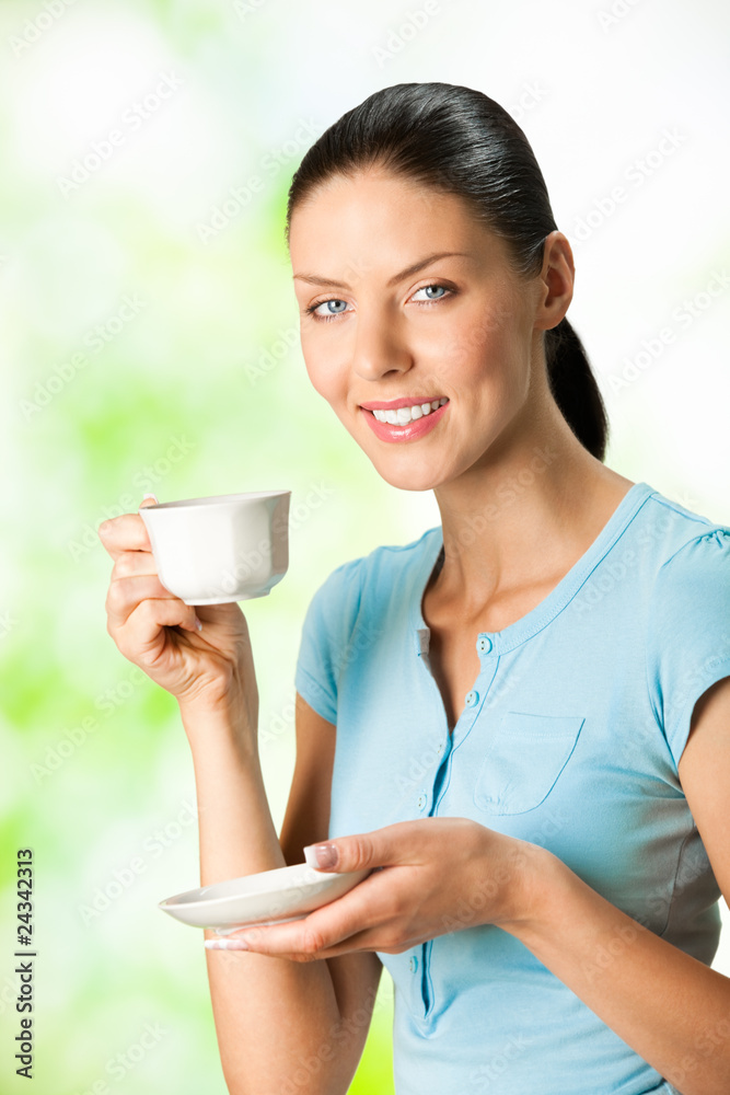 Wall mural young happy smiling woman drinking coffee, outdoors