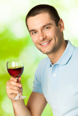 Young happy smiling man with red wine, outdoors
