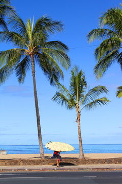 A surfer waliking along Waikiki beach