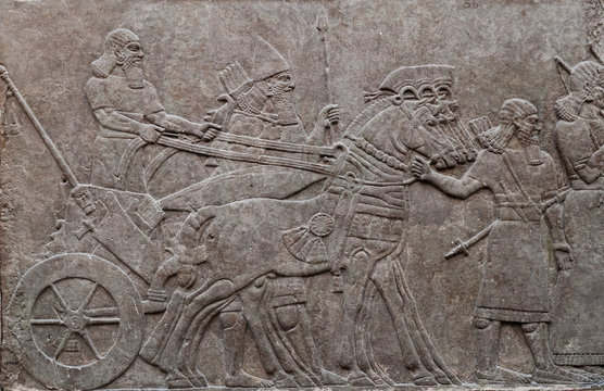 Relief of ancient assyrian warriors in a horse drawn chariot