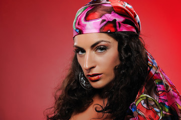 Beautiful gipsy woman with bright make-up. red background